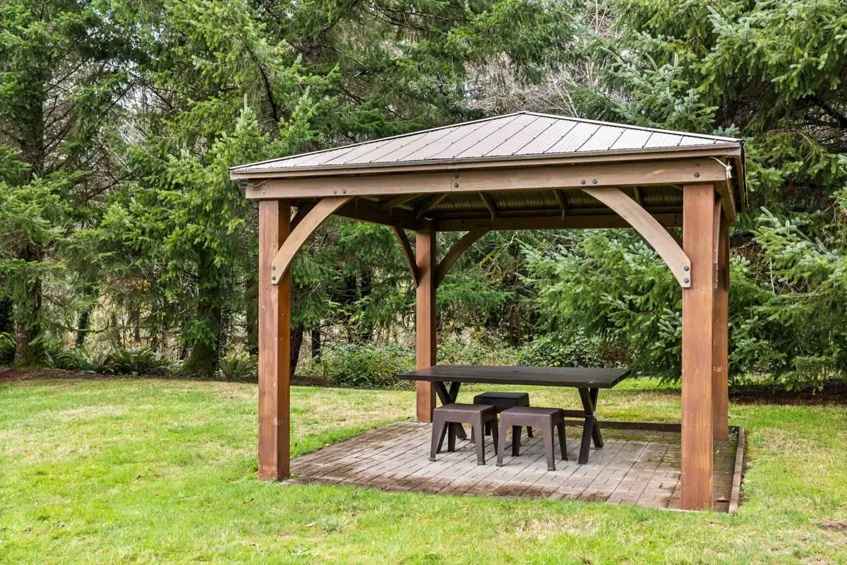 This image centers on a picturesque wooden gazebo surrounded by lush greenery, with a table and chairs set up for outdoor dining or relaxing. The setting is tranquil, inviting, and clearly shows the ample space and natural beauty described in the section.