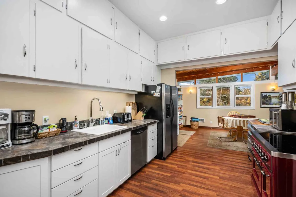 A modern kitchen filled with natural light featuring large windows, modern appliances, and wooden cabinetry. The setup is ideal for cooking and socializing, reflecting the blend of historic charm and contemporary comfort.