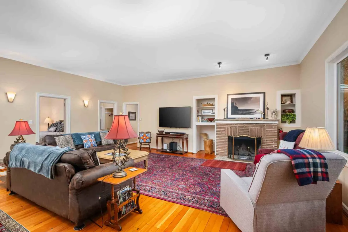 A spacious living area featuring a cozy fireplace, comfortable sofas, an area rug, and a television. The space is arranged for group activities such as family gatherings or game nights, with warm lighting that enhances the inviting atmosphere.